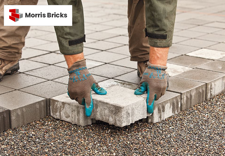Worker installing concrete paving blocks on a driveway